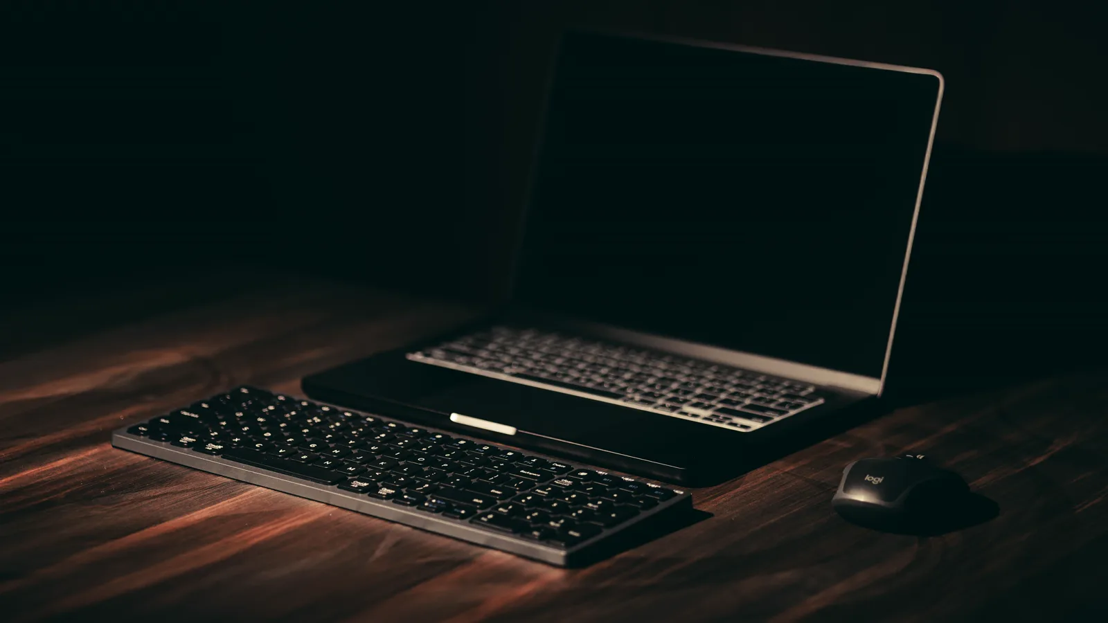 Laptop and keyboard on a dark wooden workspace